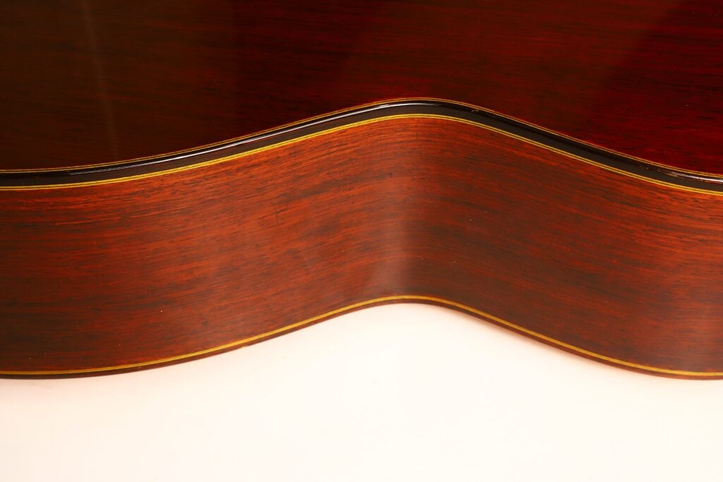 Nahaufnahme der geschwungenen Taille einer Masaru Kohno 1990 Professional J Klassische Gitarre mit dunklem Holz und dekorativen Einlagen an den Kanten. Nahaufnahme der geschwungenen Taille einer Masaru Kohno 1990 Professional J Klassische Gitarre mit dunklem Holz und dekorativen Einlagen an den Kanten.