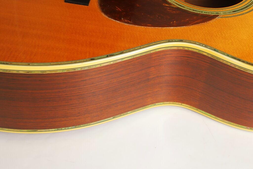 Nahaufnahme des Holzkörpers und der Taille einer Martin SOM-45 Akustikgitarre aus dem Jahr 1977 mit dekorativer Einfassung an den Kanten. Nahaufnahme des Holzkörpers und der Taille einer Martin SOM-45 Akustikgitarre aus dem Jahr 1977 mit dekorativer Einfassung an den Kanten.