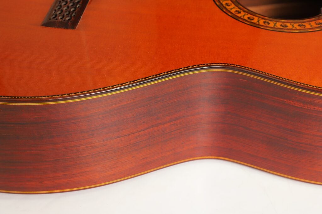 Nahaufnahme des Holzkörpers der Hopf Gran Concertio 2000 Klassische Gitarre, die die Decke, die Zargen und die Zierintarsien um das Schallloch herum zeigt. Nahaufnahme des Holzkörpers der Hopf Gran Concertio 2000 Klassische Gitarre, die die Decke, die Zargen und die Zierintarsien um das Schallloch herum zeigt.