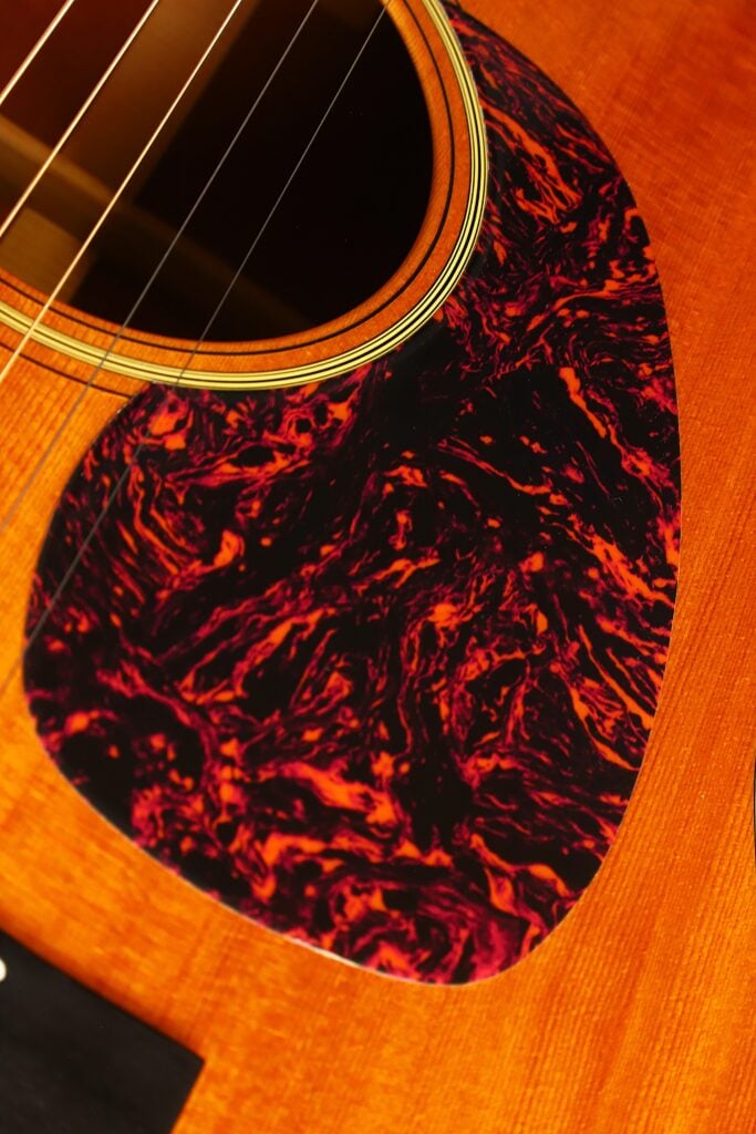 Nahaufnahme des Schalllochs und des dunklen, marmorierten, rot-schwarzen Schildpatt-Schlagbretts einer Martin D-18 VS 2006 Akustikgitarre. Nahaufnahme des Schalllochs und des dunklen, marmorierten, rot-schwarzen Schildpatt-Schlagbretts einer Martin D-18 VS 2006 Akustikgitarre.