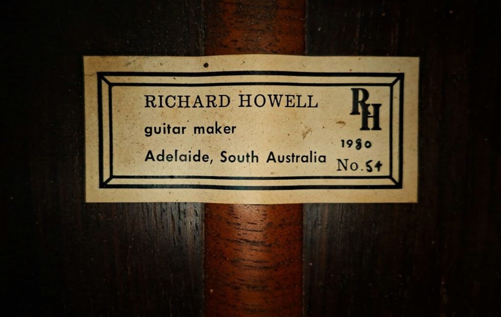 Ein rechteckiges Etikett auf einer Klassische Gitarre von Richard Howell aus dem Jahr 1980 mit der Aufschrift Richard Howell, Gitarrenbauer, Adelaide, Südaustralien, 1980, Nr. 54, rechts davon die Initialen RH. Ein rechteckiges Etikett auf einer Klassische Gitarre von Richard Howell aus dem Jahr 1980 mit der Aufschrift Richard Howell, Gitarrenbauer, Adelaide, Südaustralien, 1980, Nr. 54, rechts davon die Initialen RH.
