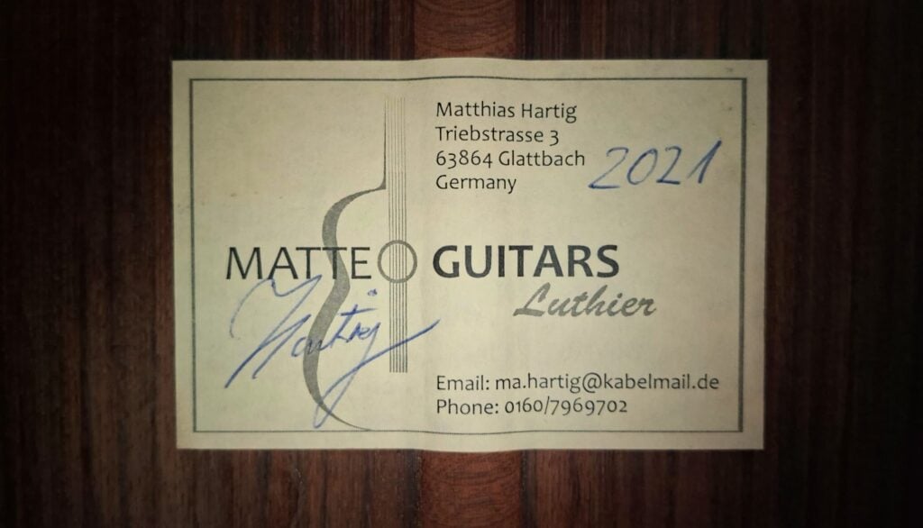 Etikett einer Torres Klassische Gitarre von Matthias Hartig aus dem Jahr 2021 mit Angabe der Adresse, der Kontaktdaten, des Jahres 2021 und einer Unterschrift. Etikett einer Torres Klassische Gitarre von Matthias Hartig aus dem Jahr 2021 mit Angabe der Adresse, der Kontaktdaten, des Jahres 2021 und einer Unterschrift.