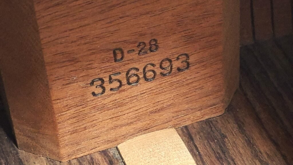Nahaufnahme des inneren Holzblocks einer Martin D-28 Akustikgitarre aus dem Jahr 1975, versehen mit der Aufschrift D-28 und der Seriennummer 356693. Nahaufnahme des inneren Holzblocks einer Martin D-28 Akustikgitarre aus dem Jahr 1975, versehen mit der Aufschrift D-28 und der Seriennummer 356693.