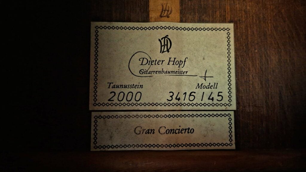 Ein rechteckiges Papieretikett für eine Hopf Gran Concertio 2000 Klassische Gitarre mit Zierrand, auf dem die Aufschrift Dieter Hopf, 2000, 3416 / 145 sowie Gran Concierto zu sehen ist. Ein rechteckiges Papieretikett für eine Hopf Gran Concertio 2000 Klassische Gitarre mit Zierrand, auf dem die Aufschrift Dieter Hopf, 2000, 3416 / 145 sowie Gran Concierto zu sehen ist.