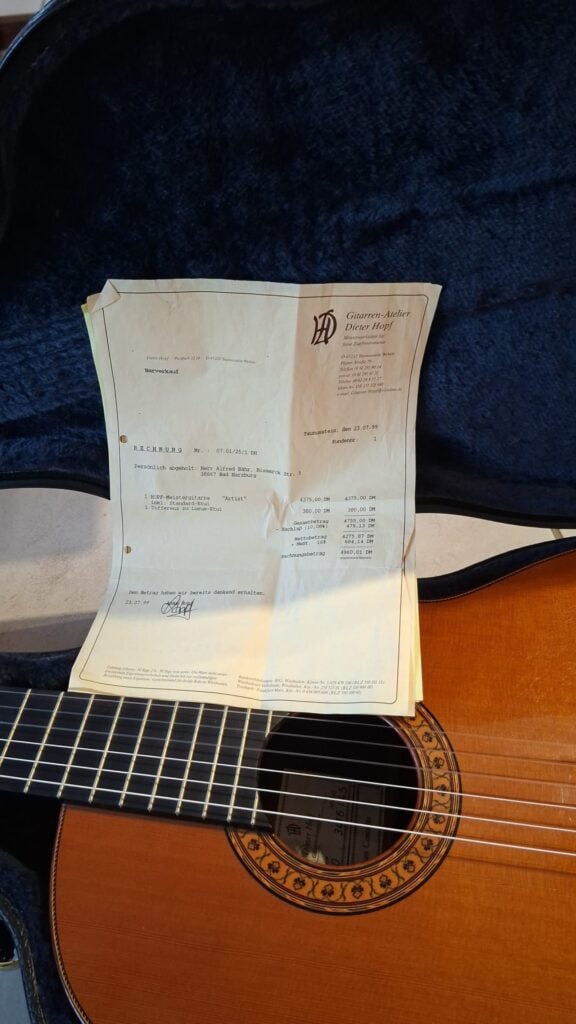 Eine Hopf Gran Concertio 2000 Klassische Gitarre in ihrem Koffer, auf deren Korpus eine alte, detaillierte Verkaufsrechnung liegt. Eine Hopf Gran Concertio 2000 Klassische Gitarre in ihrem Koffer, auf deren Korpus eine alte, detaillierte Verkaufsrechnung liegt.